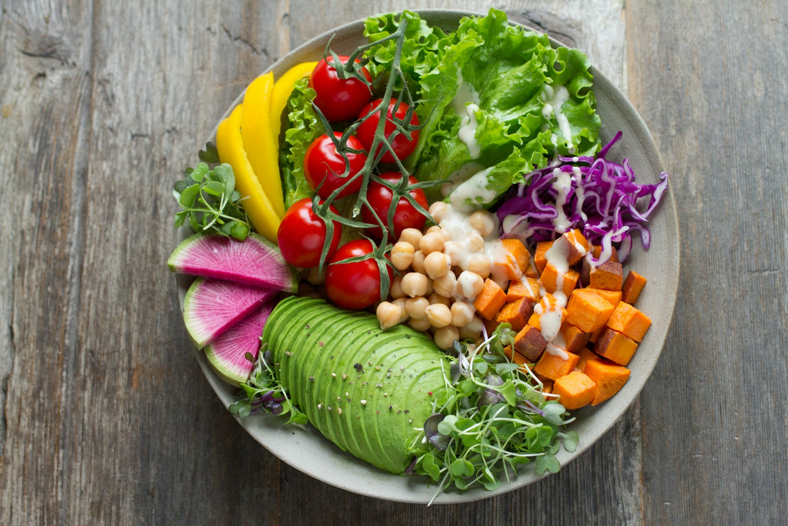 Bunte Nourish-Bowl mit Avocado, Tomaten, Kichererbsen und Süßkartoffel